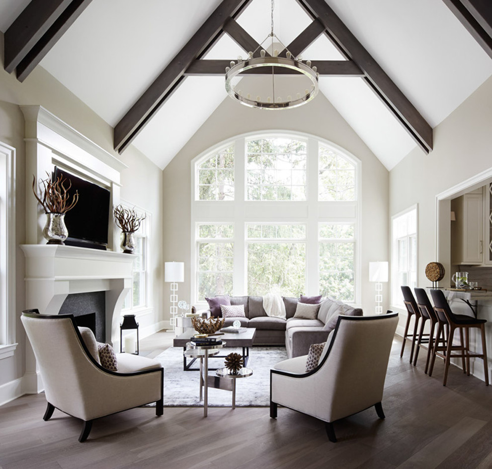 Diseño de sala de estar abierta tradicional renovada con paredes beige, suelo de madera en tonos medios, todas las chimeneas y televisor colgado en la pared