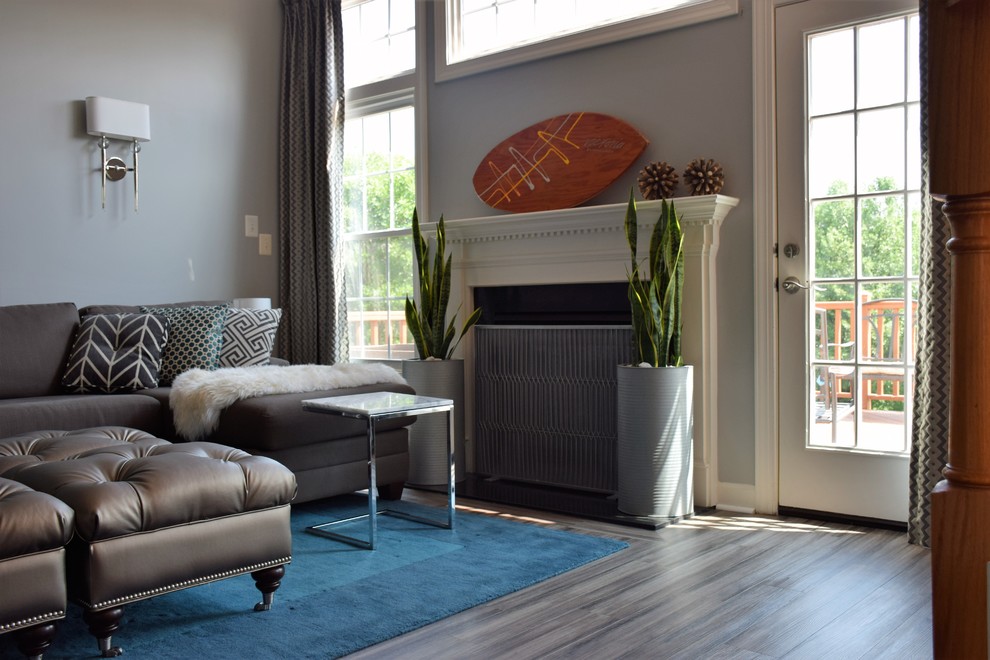 Ejemplo de sala de estar abierta tradicional renovada grande con paredes grises, suelo vinílico, todas las chimeneas, marco de chimenea de madera y televisor colgado en la pared