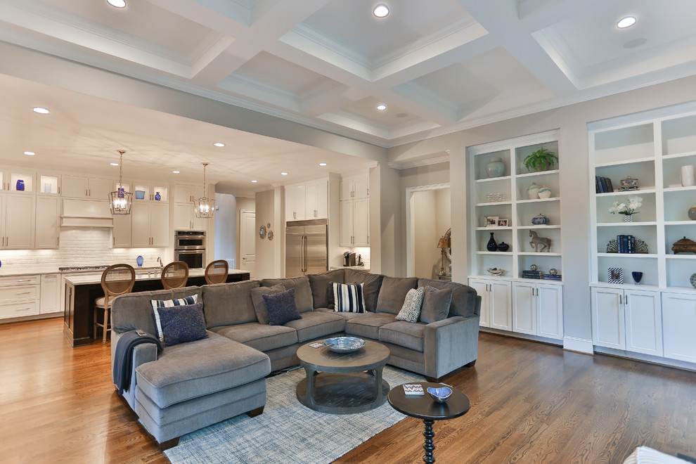 Family room - mid-sized transitional open concept medium tone wood floor family room idea in Raleigh with a wall-mounted tv, gray walls, a standard fireplace and a wood fireplace surround