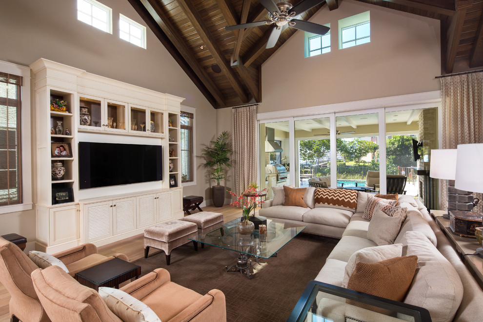 Family room - mid-sized transitional open concept light wood floor family room idea in Miami with beige walls, no fireplace and a wall-mounted tv