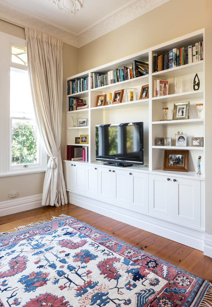 Foto de sala de estar abierta clásica renovada de tamaño medio sin chimenea con paredes amarillas, suelo de madera en tonos medios y televisor independiente
