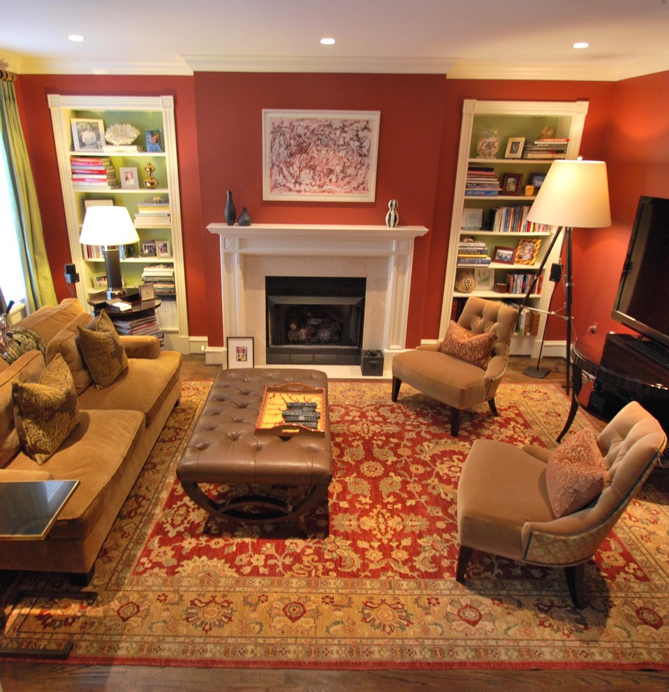 Imagen de sala de estar con biblioteca cerrada clásica renovada de tamaño medio con paredes rojas, suelo de madera oscura, todas las chimeneas, marco de chimenea de piedra, televisor independiente y suelo marrón
