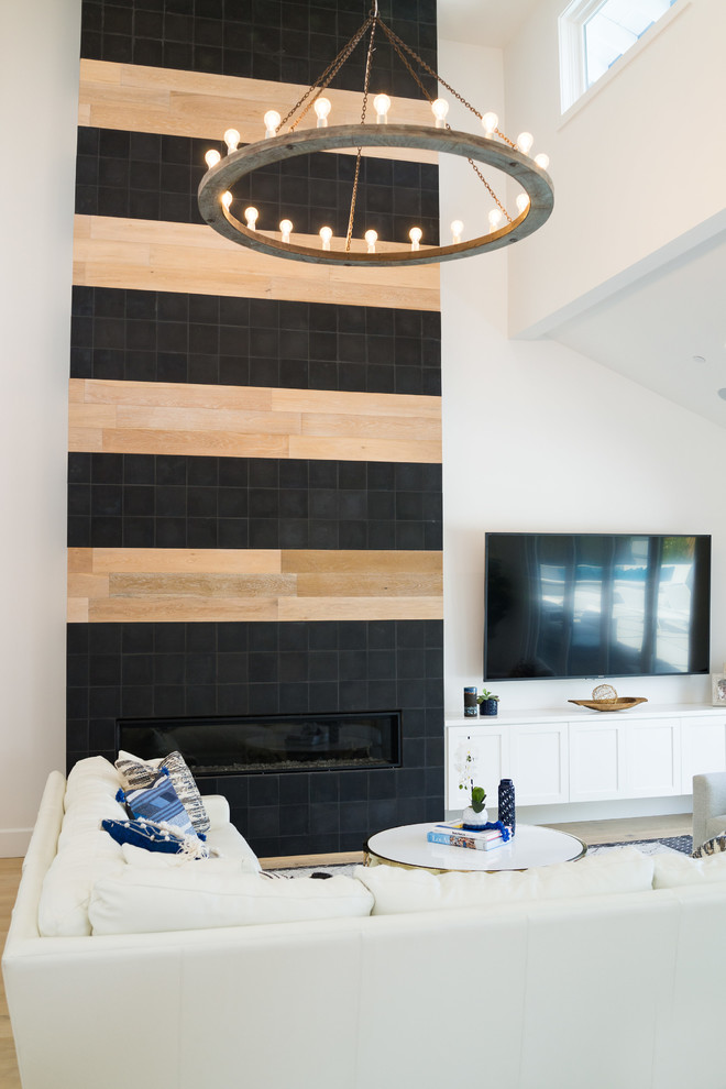 Ejemplo de sala de estar abierta tradicional renovada de tamaño medio con paredes blancas, chimenea lineal, marco de chimenea de baldosas y/o azulejos y televisor colgado en la pared