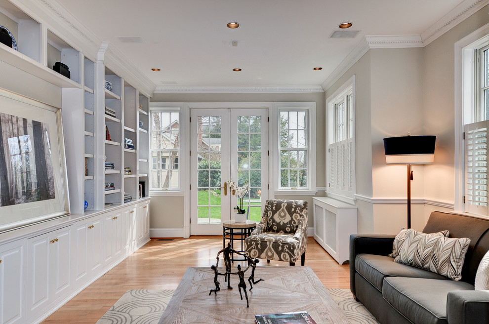 Example of a mid-sized classic enclosed light wood floor and brown floor family room design in DC Metro with white walls and no fireplace