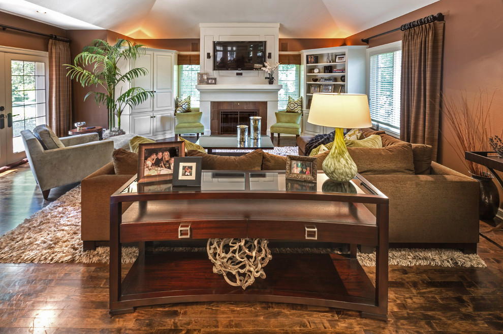 Example of a mid-sized transitional enclosed dark wood floor family room library design in Milwaukee with brown walls, a standard fireplace, a stone fireplace and a media wall