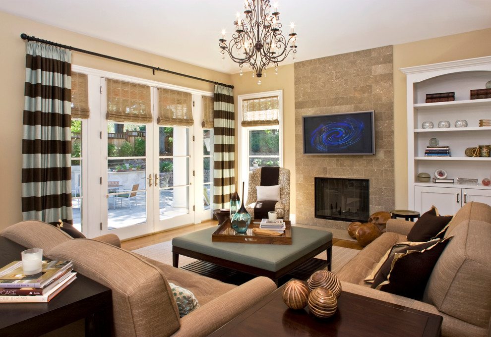 Modelo de sala de estar tradicional con paredes beige, suelo de madera en tonos medios, todas las chimeneas y televisor colgado en la pared