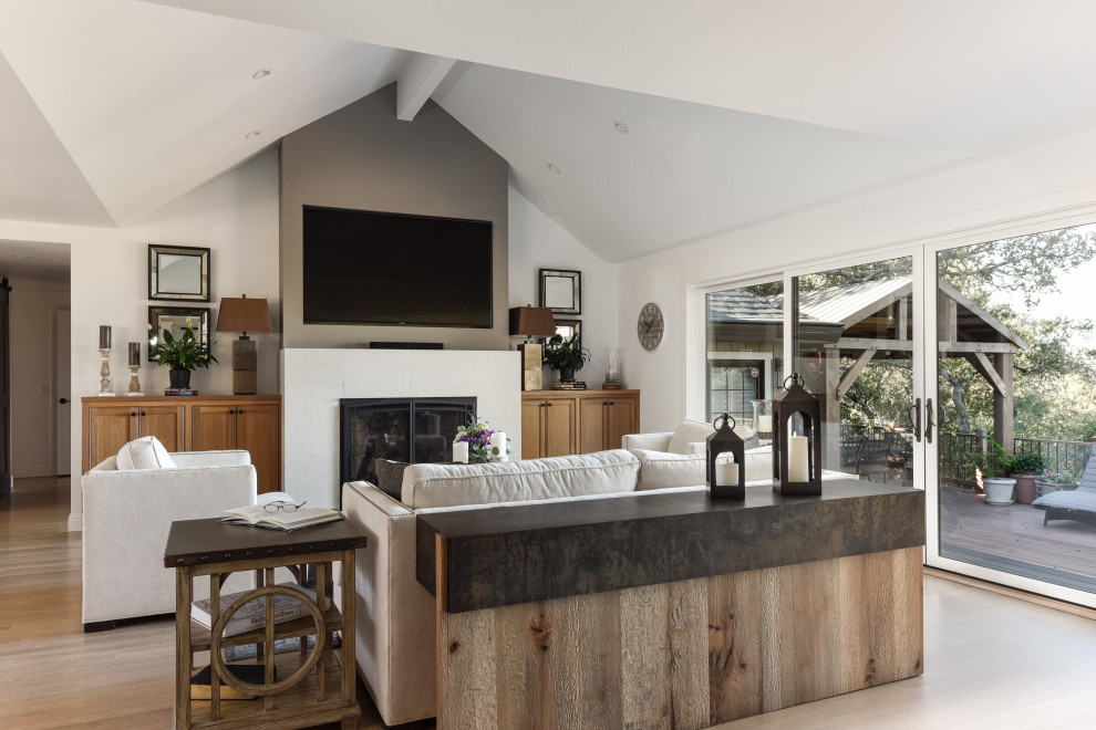 Inspiration pour une salle de séjour traditionnelle ouverte avec un mur blanc, un sol en bois brun, une cheminée standard, un téléviseur fixé au mur, un sol marron et un plafond voûté.