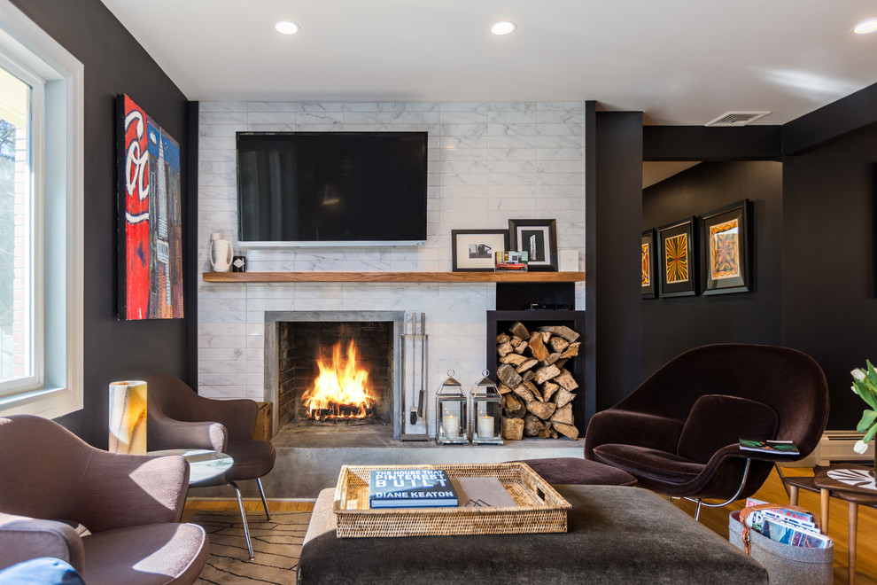 Mittelgroßes, Abgetrenntes Klassisches Wohnzimmer mit schwarzer Wandfarbe, braunem Holzboden, Kamin, gefliester Kaminumrandung, TV-Wand und braunem Boden in New York