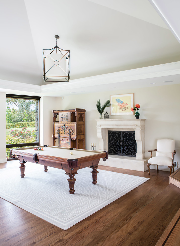 Inspiration for a traditional games room in San Diego with beige walls, medium hardwood flooring, a standard fireplace and brown floors.