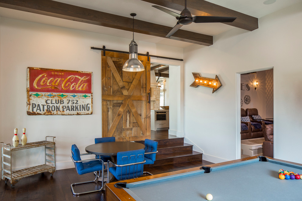 This is an example of a large farmhouse enclosed games room in Austin with white walls, dark hardwood flooring, no fireplace, a stone fireplace surround, a wall mounted tv and a game room.