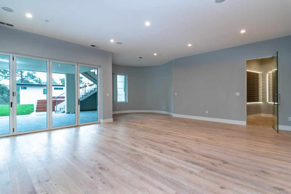 Example of a large transitional open concept light wood floor and white floor game room design in San Francisco with gray walls, a standard fireplace, a tile fireplace and a media wall