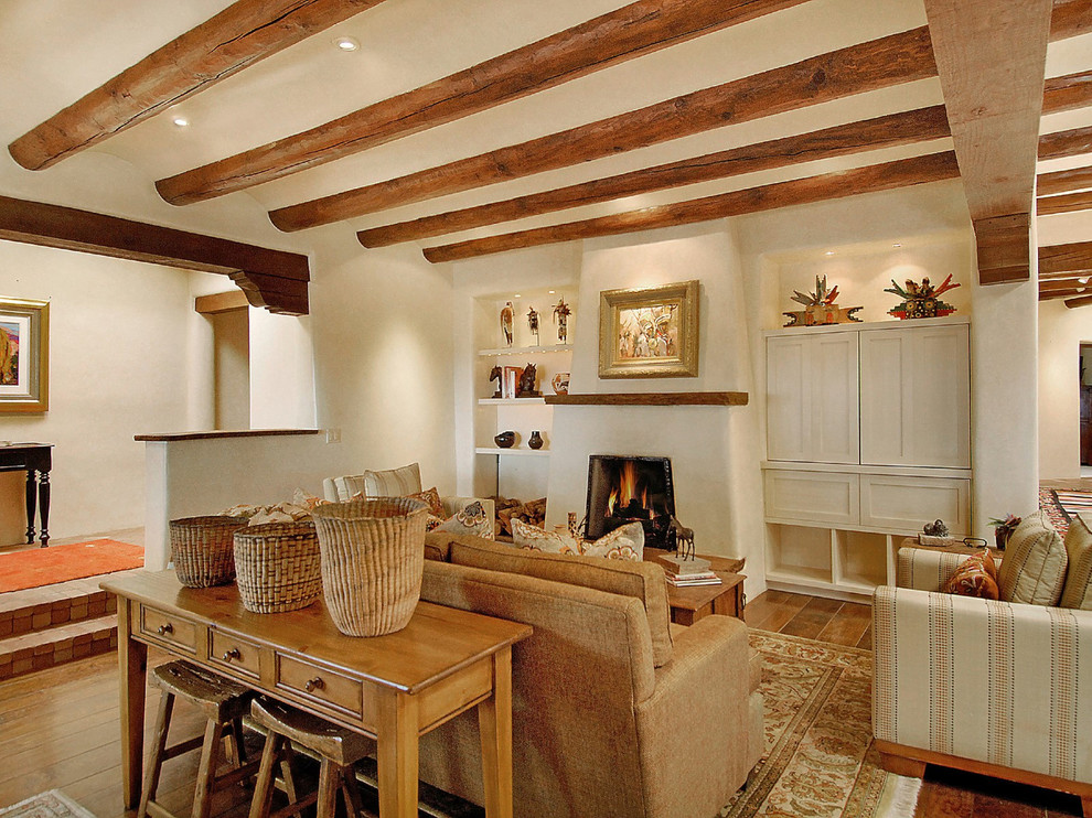 Modelo de sala de estar clásica renovada de tamaño medio sin televisor con paredes blancas, suelo de madera en tonos medios, todas las chimeneas y marco de chimenea de yeso