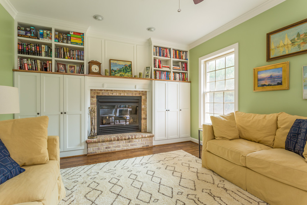 Exemple d'une grande salle de séjour craftsman avec une bibliothèque ou un coin lecture, un mur vert, parquet foncé, une cheminée standard et un manteau de cheminée en brique.