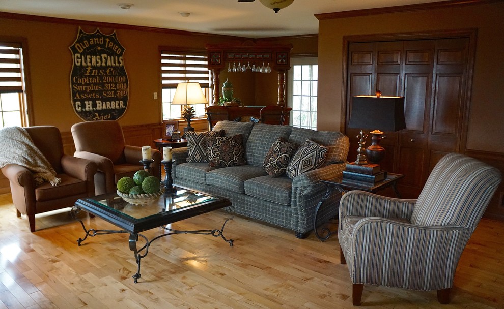 Imagen de sala de estar con barra de bar abierta rústica grande con paredes marrones y suelo de madera clara