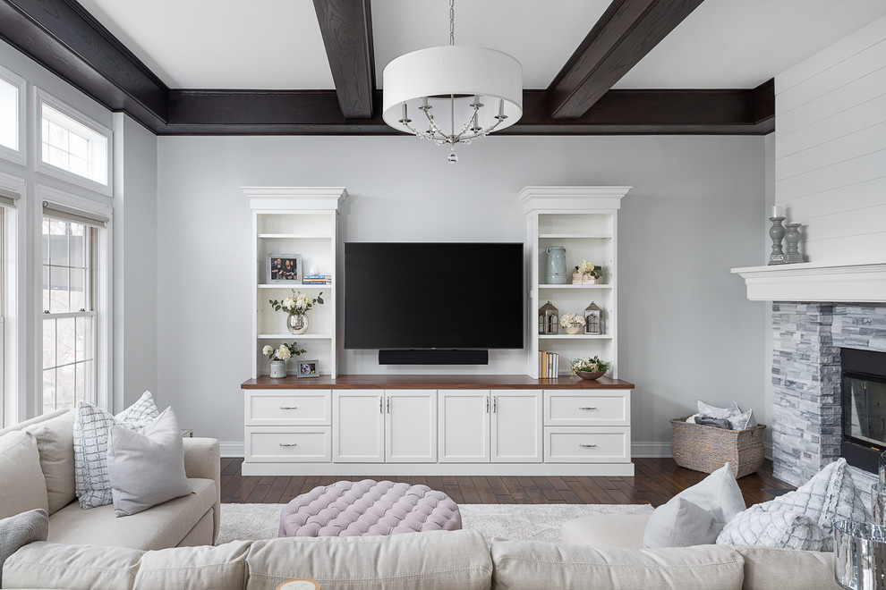 Foto de sala de estar abierta clásica renovada grande con paredes grises, suelo de madera oscura, chimenea de doble cara, marco de chimenea de piedra, televisor colgado en la pared y suelo marrón