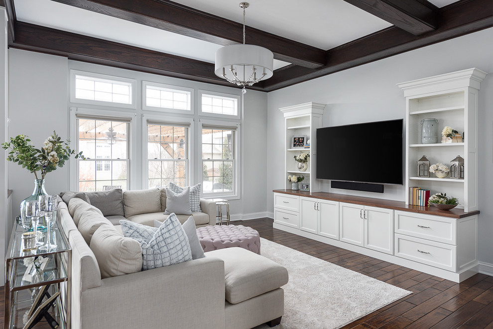 На фото: большая гостиная комната в стиле неоклассика (современная классика) с серыми стенами, темным паркетным полом, телевизором на стене, коричневым полом и ковром на полу