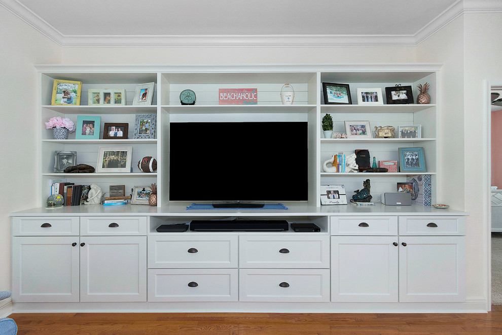 Imagen de sala de estar abierta tradicional renovada de tamaño medio sin chimenea con paredes beige, suelo de madera en tonos medios, pared multimedia y suelo marrón