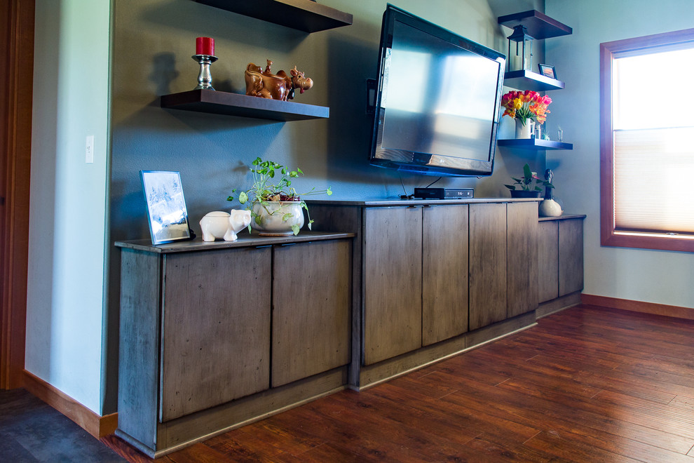 Modelo de sala de estar abierta clásica renovada de tamaño medio sin chimenea con paredes verdes, suelo de madera en tonos medios y televisor colgado en la pared