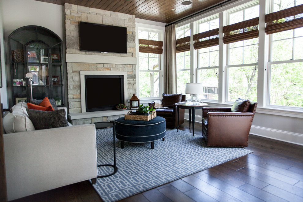 Modelo de sala de estar tradicional renovada con suelo de madera oscura, todas las chimeneas, marco de chimenea de piedra, suelo marrón y alfombra