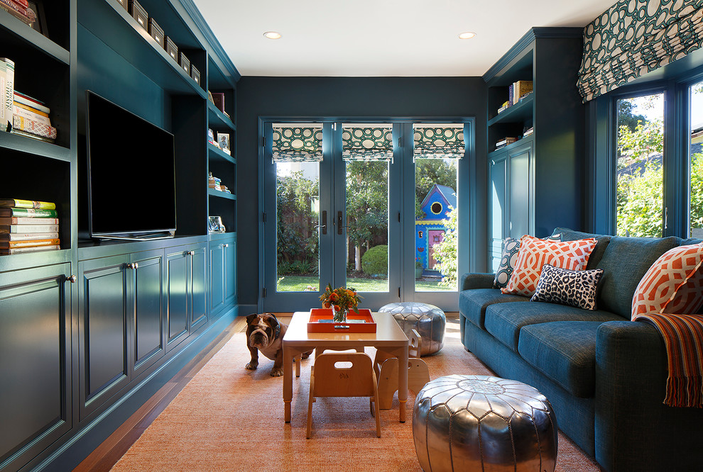 Modelo de sala de estar con biblioteca cerrada clásica renovada pequeña sin chimenea con paredes azules, suelo de madera en tonos medios, pared multimedia y alfombra