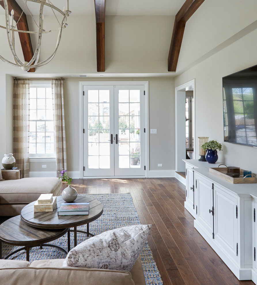 Modelo de sala de estar abierta tradicional renovada de tamaño medio sin chimenea con paredes grises, suelo laminado, televisor colgado en la pared y suelo marrón