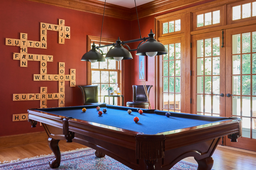 This is an example of a classic open plan games room in New York with red walls, medium hardwood flooring and brown floors.