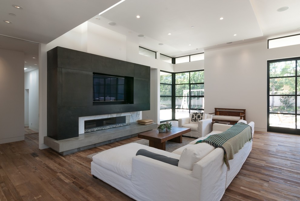 This is an example of a medium sized modern open plan games room in San Diego with white walls, a ribbon fireplace, a stone fireplace surround, a built-in media unit and medium hardwood flooring.