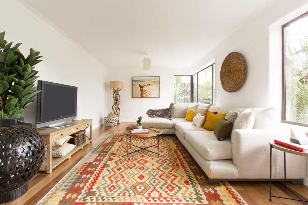Mittelgroßes Wohnzimmer mit weißer Wandfarbe, braunem Holzboden, freistehendem TV und beigem Boden in Sydney