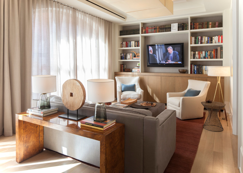 Modelo de sala de estar con biblioteca cerrada clásica renovada de tamaño medio sin chimenea con paredes blancas, televisor colgado en la pared, suelo de madera clara y suelo beige