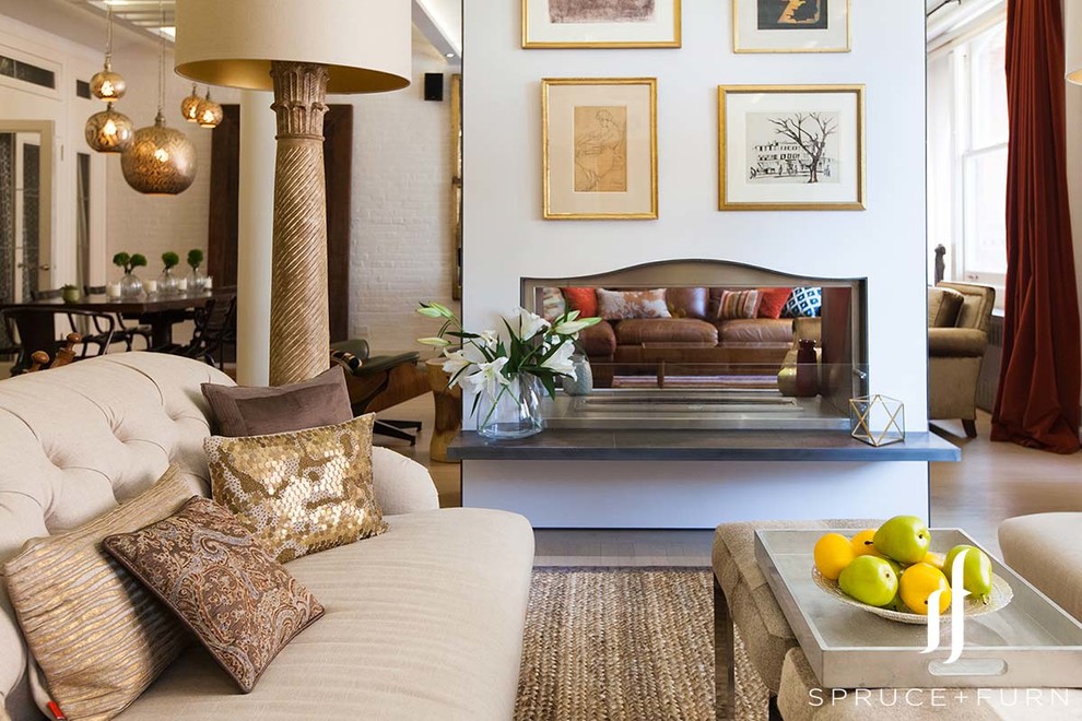 Esempio di un grande soggiorno contemporaneo aperto con pareti beige, parquet chiaro, camino bifacciale e cornice del camino in intonaco