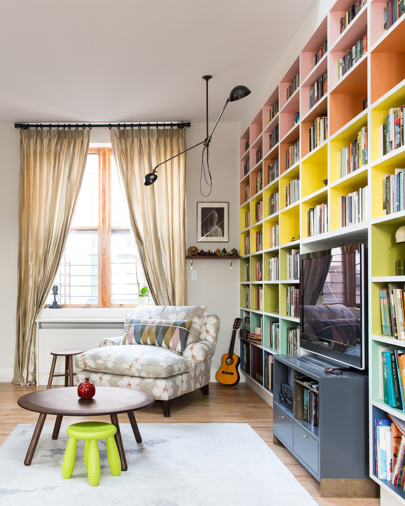 Example of a 1950s medium tone wood floor family room library design in New York with gray walls and a media wall