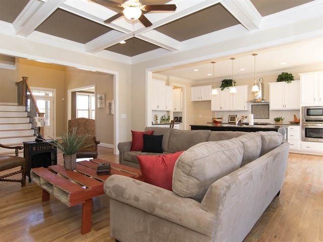 Großes, Offenes Shabby-Look Wohnzimmer mit grauer Wandfarbe, braunem Holzboden, Kamin, Kaminumrandung aus Stein und TV-Wand in Raleigh
