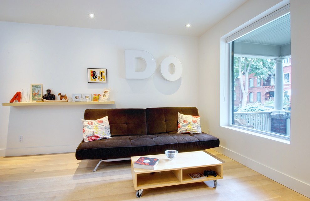 Exemple d'une salle de séjour moderne avec un mur blanc, parquet clair et canapé noir.