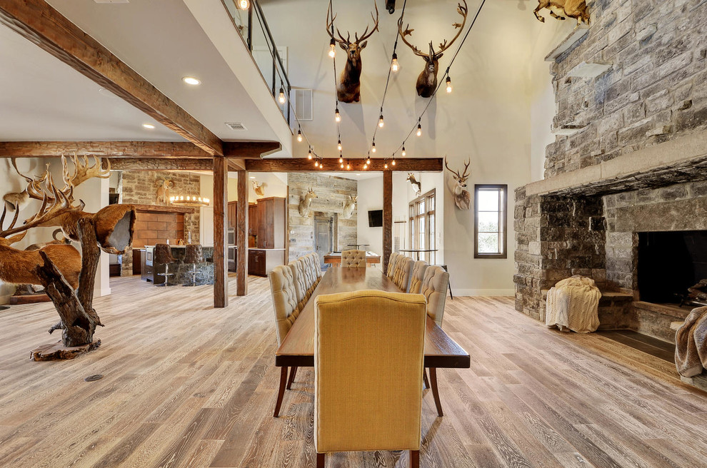 This is an example of a large rustic open plan games room in Austin with medium hardwood flooring, a standard fireplace and a stone fireplace surround.
