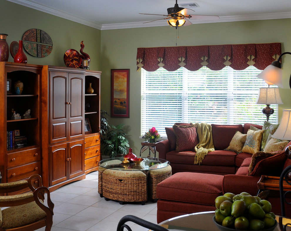 Foto de sala de estar cerrada tropical grande con paredes verdes, suelo de baldosas de porcelana y televisor retractable