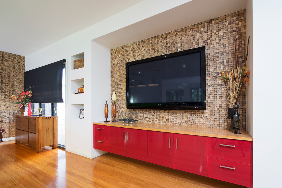 Imagen de sala de juegos en casa abierta exótica grande sin chimenea con paredes multicolor, suelo de madera en tonos medios y televisor colgado en la pared
