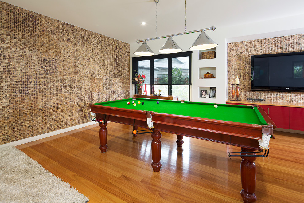 Modelo de sala de juegos en casa abierta exótica grande sin chimenea con paredes multicolor, suelo de madera en tonos medios y televisor colgado en la pared