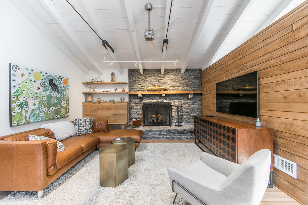 Rustikales Wohnzimmer mit weißer Wandfarbe, Kamin, Kaminumrandung aus Stein und TV-Wand in Sonstige