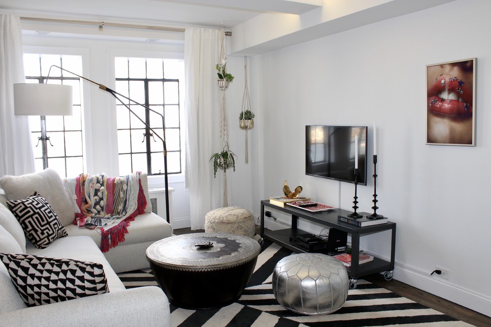 На фото: маленькая изолированная гостиная комната в стиле фьюжн с белыми стенами, темным паркетным полом, телевизором на стене и ковром на полу без камина для на участке и в саду