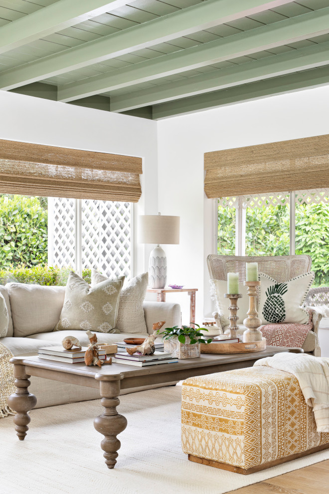 Modelo de sala de estar ecléctica con paredes blancas, suelo de madera en tonos medios, suelo marrón y vigas vistas