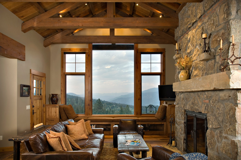 Ejemplo de sala de estar rural con marco de chimenea de piedra