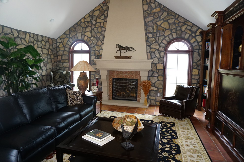 This is an example of a large mediterranean open plan games room in Philadelphia with a reading nook, terracotta flooring, a standard fireplace, a tiled fireplace surround, a built-in media unit and brown floors.