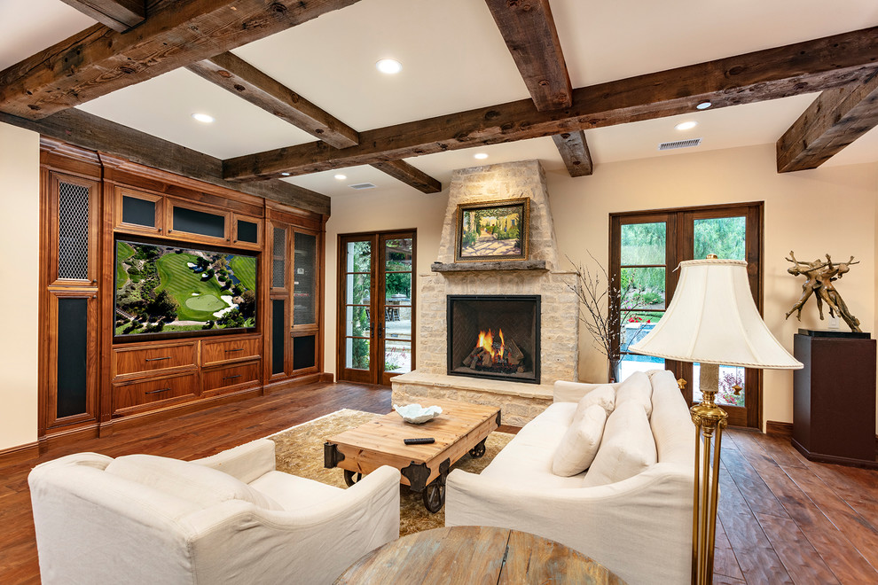 Inspiration for a mediterranean dark wood floor and brown floor family room remodel in Orange County with beige walls, a standard fireplace and a stone fireplace