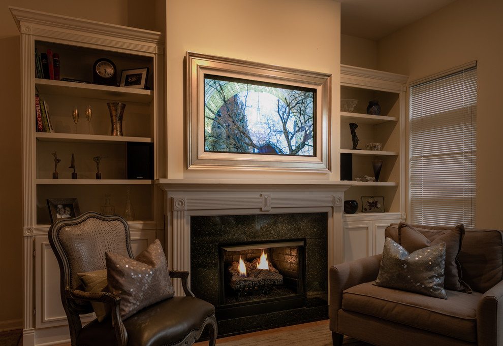 Cette photo montre une salle de séjour chic avec un mur beige, parquet clair, une cheminée standard, un manteau de cheminée en carrelage et un téléviseur dissimulé.