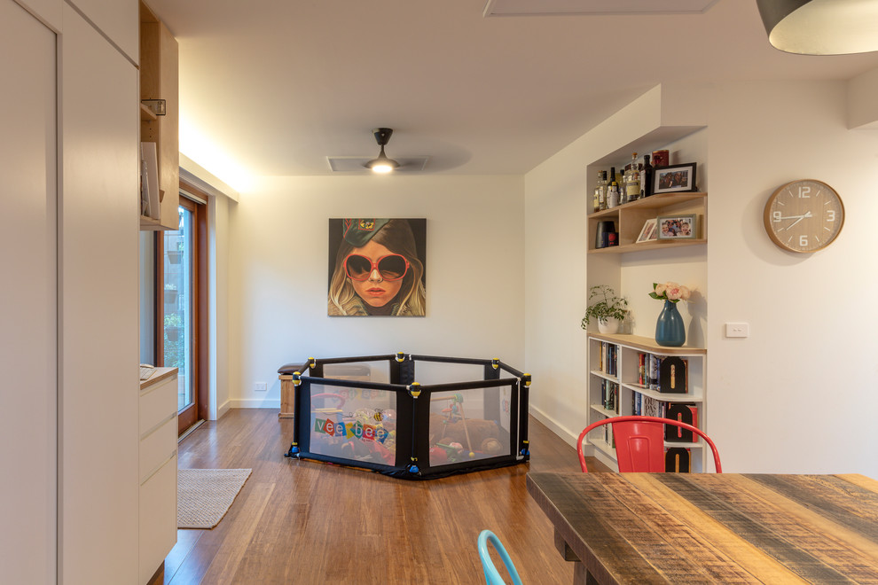 Modelo de sala de estar abierta actual pequeña sin televisor con paredes blancas, suelo de bambú y suelo marrón