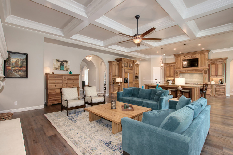 Modelo de sala de estar abierta mediterránea grande con paredes beige, suelo de madera clara y suelo marrón