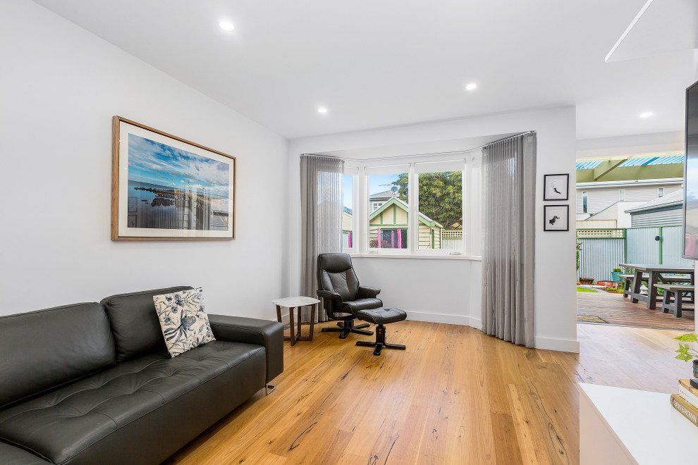 Mittelgroßes Modernes Wohnzimmer mit weißer Wandfarbe, braunem Holzboden und braunem Boden in Melbourne