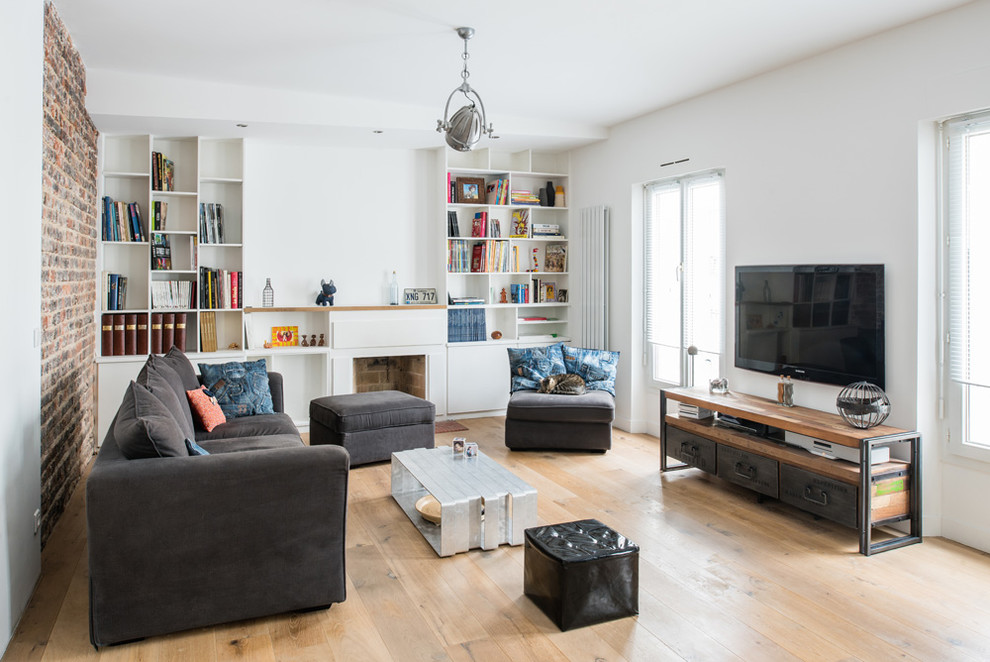This is an example of a medium sized industrial open plan games room in Paris with white walls, medium hardwood flooring, a standard fireplace, a wall mounted tv, a reading nook and a concrete fireplace surround.