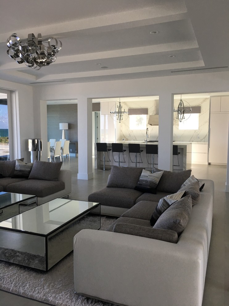 This is an example of a large contemporary open plan games room in Miami with white walls, concrete flooring, no fireplace, no tv, grey floors and exposed beams.