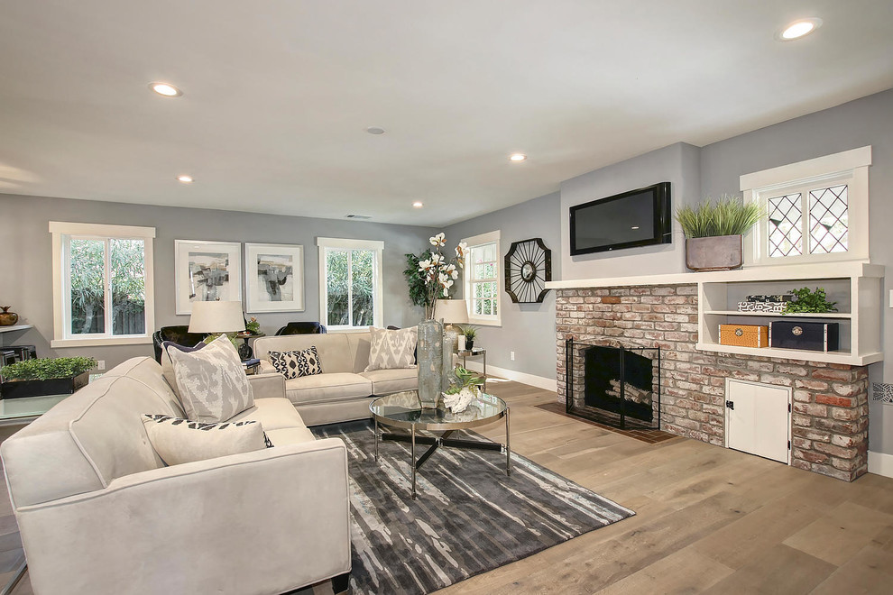 Large elegant open concept light wood floor and beige floor family room photo in Sacramento with gray walls, a standard fireplace, a brick fireplace and a wall-mounted tv